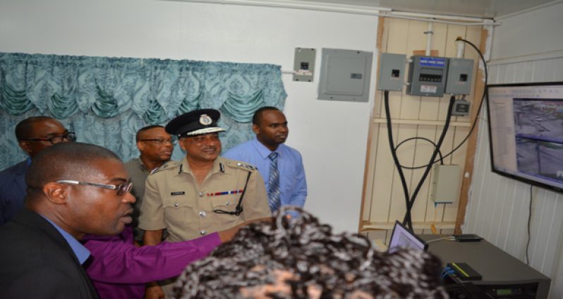 Minister David Patterson, Top Cop Seelall Persaud and Crime Chief Wendell Blanhum look on along with other officials as Crime Intelligence Officer-in-Charge Brian Adams pinpoints the many advantages of the CCTV cameras on the screens ahead