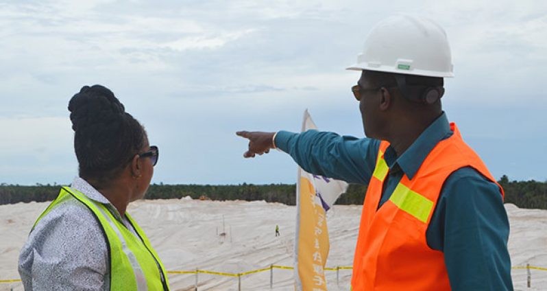 Minister Patterson points in the direction of extension works being undertaken at the south-western end of the main runway at the CJIA, as minister within the Ministry of Public Infrastructure Annette Ferguson looks on
