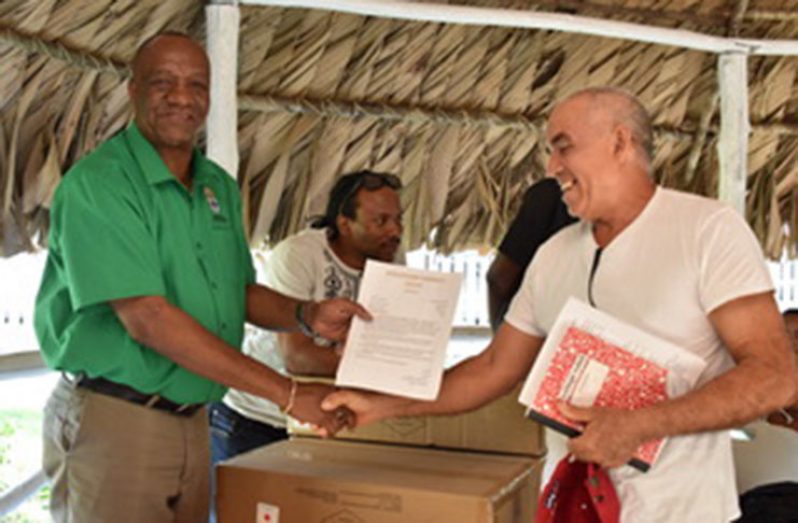 Minister of State, Joseph Harmon, hands over lights to a resident of Speightland, Region 10