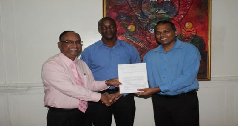 All smiles! Guyana Amazon Warriors Team Operations manager Omar Khan receives the signed document from Minister of Culture, Youth and Sport Dr Frank Anthony in the presence of Permanent Secretary Alfred King.