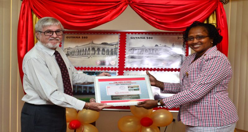 Hand-in-Hand Manager, John Carpenter as he presented First Day Covers of the stamps to Minister within the Ministry of Public Infrastructure, Annette Ferguson yesterday