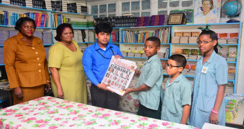 Chronicle Reporter, Navendra Seoraj hands over copies of the May 24 edition of the Sunday Chronicle to students of St. Margaret’s Primary School in the presence of two teachers