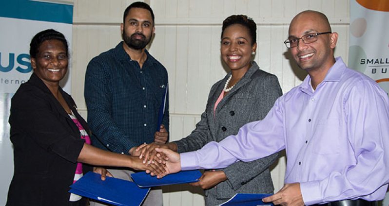Permanent Secretary, Ministry of Business Rajdai Jagarnauth; Tariq Williams, Regional Programme Officer, Cuso International; Valrie Grant, Managing-Director, GeoTechVision Guyana; and Vishnu Doerga, President, Georgetown Chamber of Commerce & Industry, shake hands after signing a Memorandum of Understanding to establish a Business Incubation Centre in Guyana (Photo credit: Cuso International)