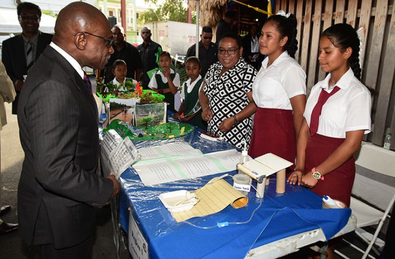 Acting President and Minister of Foreign Affairs, Carl Greenidge learns about the ‘Gravity Float’ project from students and this teacher from the North West Secondary School