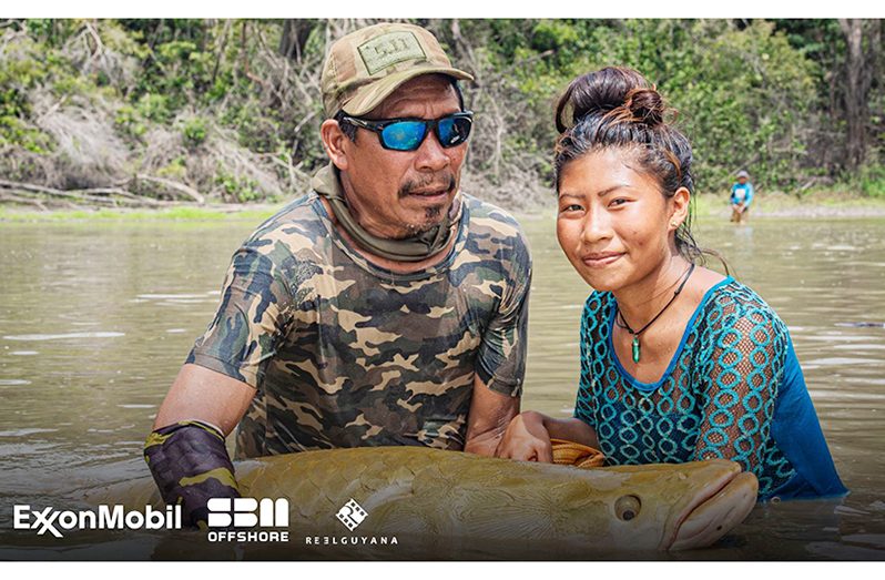 Campbell James and a student of Apoteri Village in the rescue efforts of atrapped arapaima in a shallow pond.