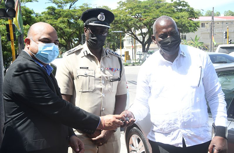 Chief executive officer (CEO) of the Palm Court Group of Companies, Ravin Prashad, hands over the keys to the cars to Minister of Home Affairs, Robeson Benn, as Commissioner of Police (ag) Nigel Hoppie looks on (Adrian Narine photo)