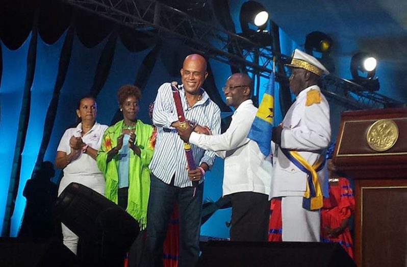 Former Haitian President Michel Martelly hands over the CARIFESTA baton created by acclaimed Haitian Visual Artist Phillipe Dodard, to Barbados Minister of Culture, Sport and Youth, Stephen Lashley