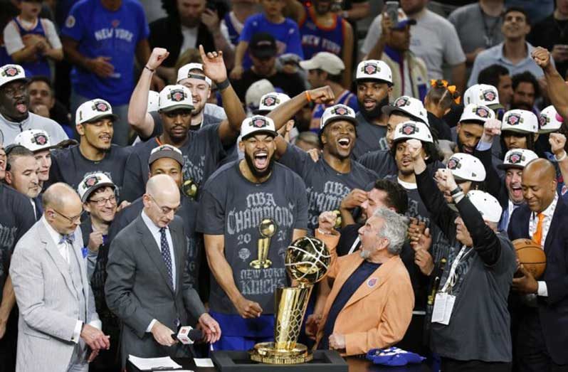 Karl-Anthony Towns #32 of the New York Knicks and team owner James Dolan celebrate behind the Larry O'Brien Championship Trophy after the victory against the San Antonio Spurs in Game Five of the 2026 NBA Finals at Frost Bank Center on last Saturday night.