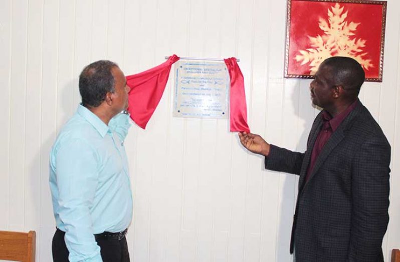 Kent Vincent, CEO of Food for the Poor Guyana Inc., unveils the plaque with Dr. Marlon Hestic, senior pastor for the Vreed-en-Hoop Wesleyan Church last Saturday.