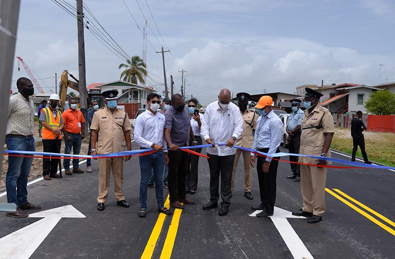 Minister of Public Works, Bishop Juan Edghill, with the aid of contractor, Matthew Vieira (first from left holding ribbon) and City Engineer, Colvern Venture (second from left holding ribbon), cuts the ceremonial ribbon to officially reopen Hunter Street, as other officials look on (Delano Williams Photo)