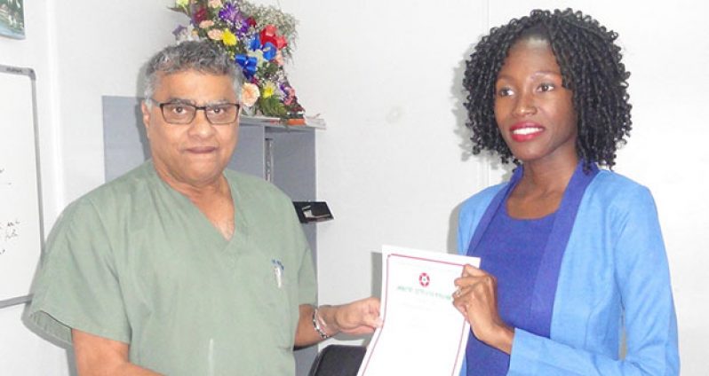 Tashi Meville Browne of the GNBS presents certificate to Dr. Neville Gobin of the Woodlands Hospital