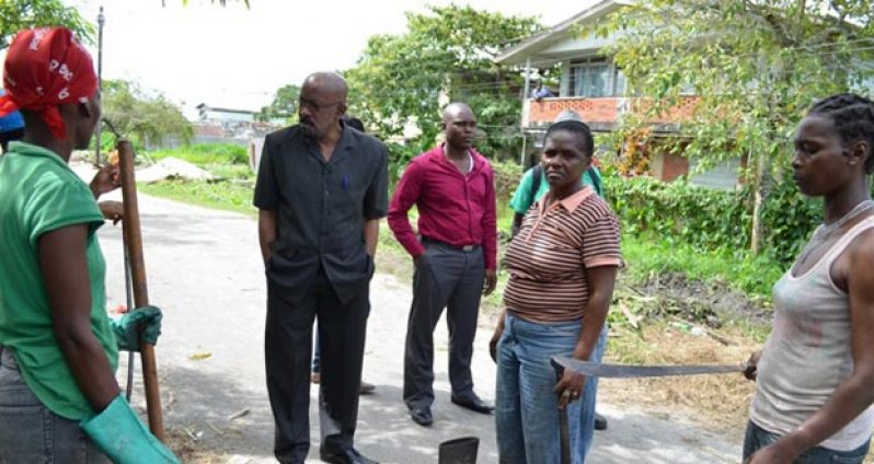 Minister within the Ministry of Local Government and Regional Development, Norman Whittaker, interacts with workers in one of the communities where the sprucing up is being conducted