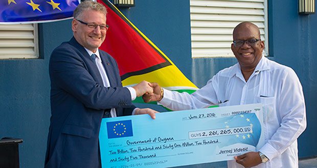 Ambassador Jernej Videtic presenting the cheque, worth Gy$2.261B, to Finance Minister Winston Jordan for improvement of the country’s sea and river defences