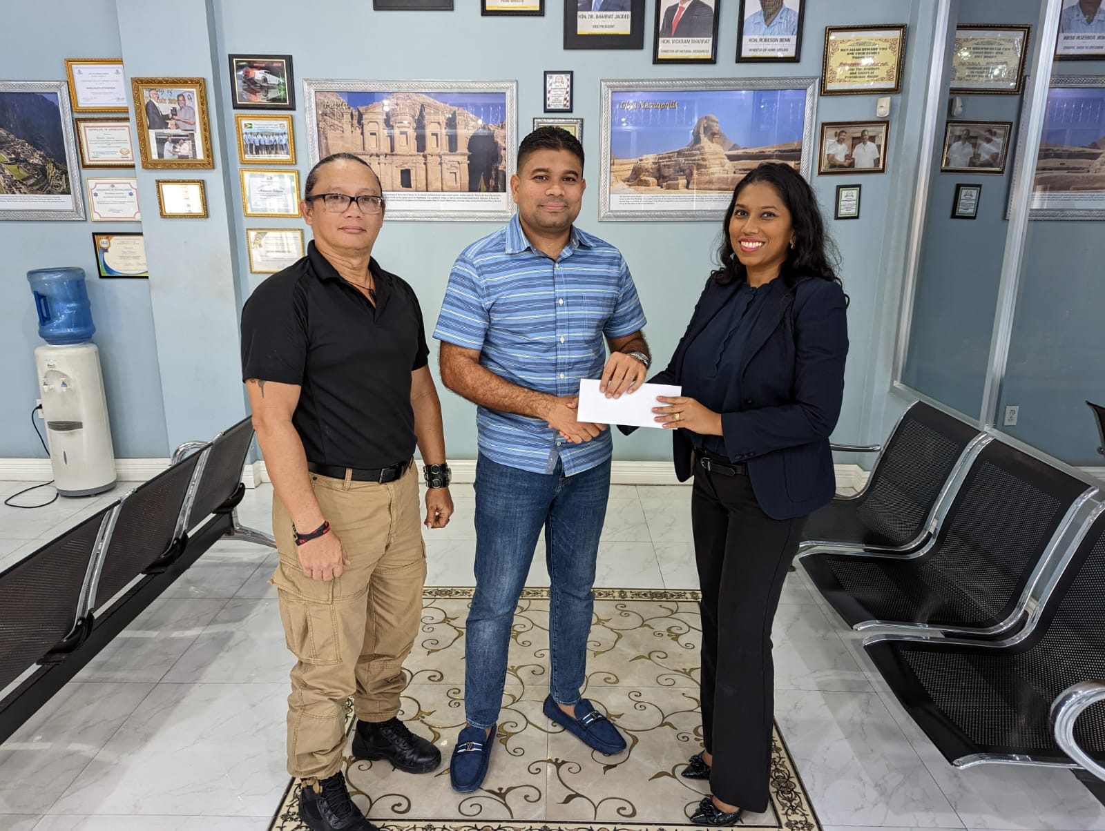 Mr. Azruddin Mohamed (at centre) hands over sponsorship cheque to Mrs. Vidushi Persaud-McKinnon, Secretary-General of Archery Guyana (at right). At left is Mr. Nicholas Hing, head-coach of Archery Guyana
