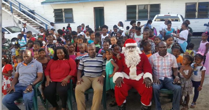 Commander Edmond Cooper (seated at centre) flanked by children and participants of the special Christmas gathering