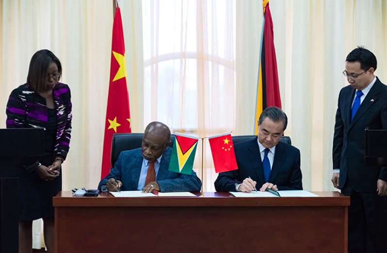 Minister of Foreign Affairs Carl Greenidge and State Councillor and Minister of Foreign Affairs of the People’s Republic of China, Wang Yi, as they sign one of several agreements on last month at the Arthur Chung Convention Centre at Liliendaal. (Delano Williams photo)