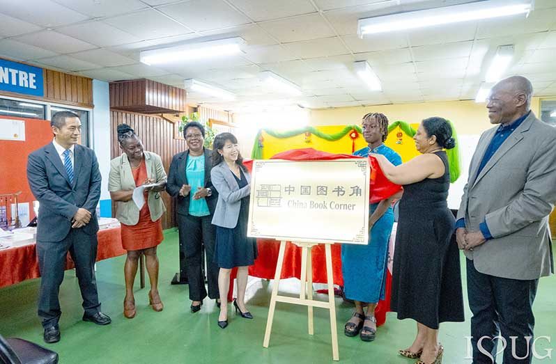 University of Guyana’s Vice-Chancellor, Professor Paloma Mohamed Martin, and China’s Ambassador to Guyana, Her Excellency Yang Yang, remove the ceremonial covering to officially unveil the China Book Corner signage at the University of Guyana Library, Turkeyen Campus. They are joined by senior members of the University of Guyana, representatives of the Embassy of the People’s Republic of China in Guyana, and a student of the University during the unveiling ceremony on Monday, June 15, 2026