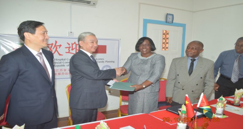 Minister within the Ministry of Public Health, Dr Karen Cummings, and Chinese Ambassador to Guyana, Zhang Limin, shake hands following the signing of the certificates of donation at the GPHC Resource Centre. Vice- President and Foreign Affairs Minister Carl Greenidge, and Leader of the Chinese Delegation, Lang Qing, look on