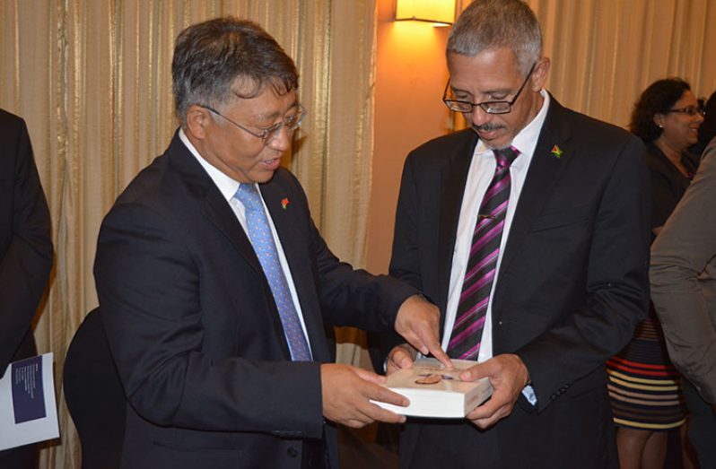 China's Ambassador to Guyana, Mr. Cui Jianchun, shares a book on  governance of China with Minister of Business Dominic Gaskin at the cocktail reception (Rabindra Rooplall photo)