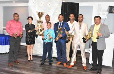 Consul General Anyin Choo hands over the Division A championship trophy to Sunshine skipper Anil Mahadeo in the presence of some players and manager Paris Tulsi (extreme right).