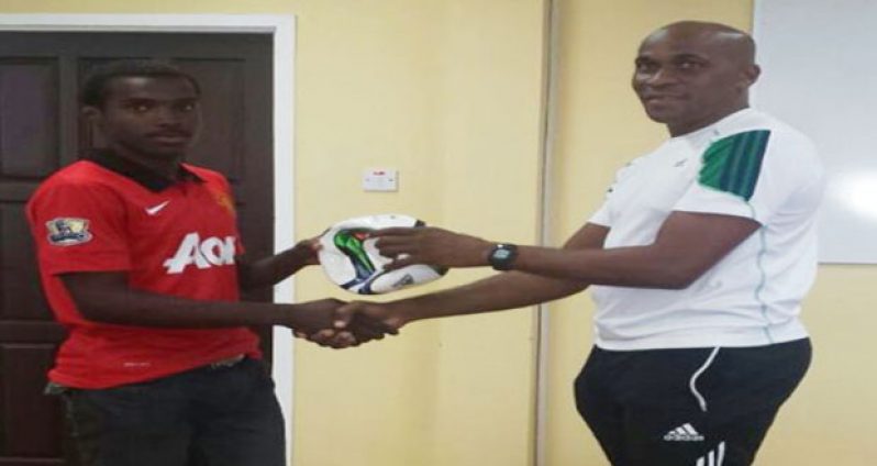 Robert Christiani (left) receives a ball as a token from GFF head of referees Stanley Lancaster.