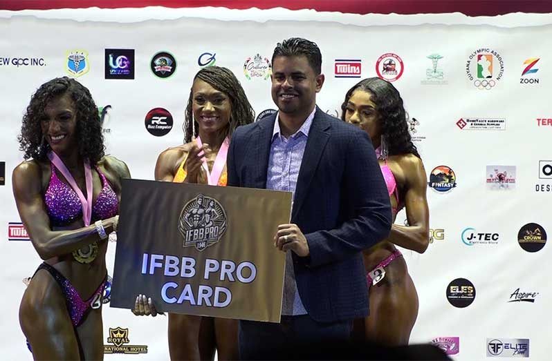 One Guyana Stage of Champion Ms. Bikini winner, Christina Ramsammy (third right) collecting pro-card from Minister Charles Ramson jr. Also in photo are: GBBFF President Roger Callender; organisers Keavon Bess, Videsh Sookram, and Fizal Bacchus, along with second and third-place Ms. Bikini athletes