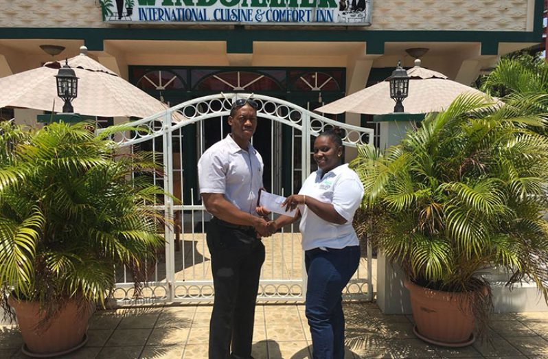 Former Mr Guyana, Kerwin Clarke, collects his sponsorship cheque from Lucette Borune.
