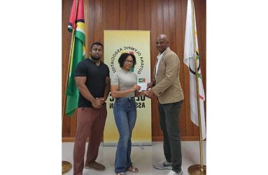 Videsh Sookram and Melitha Anderson collecting sponsorship from GOA president Godfrey Munroe