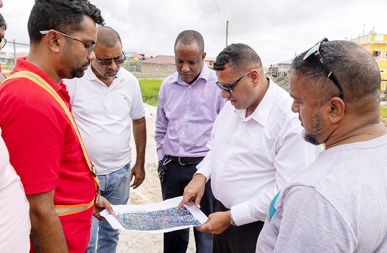 Minister of Housing and Water, Collin Croal and a team inspect a map of the area