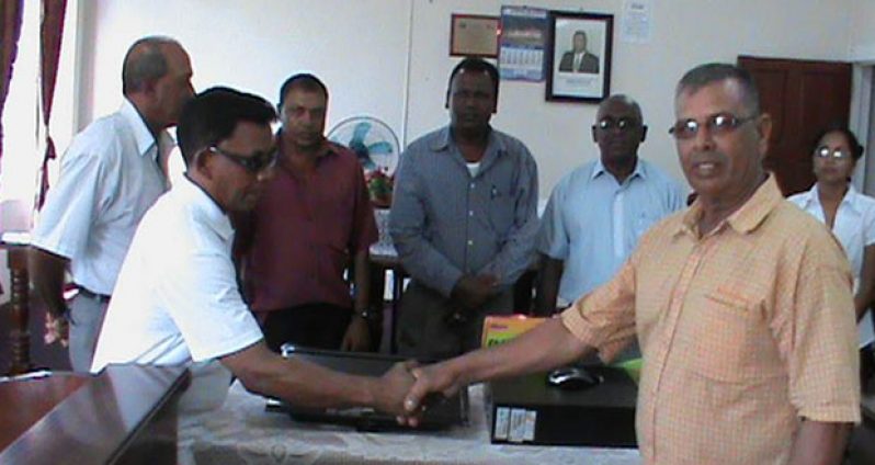 IMC Councillor Abrahim Baksh handing over the computer to Chairman of the IMC, Mr Toolsie Narine in the Anna Regina Town Council Boardroom