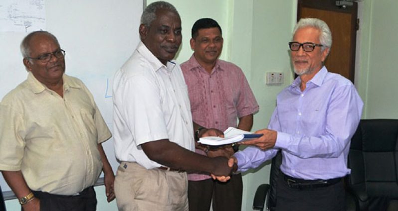 Minister of Public Works, Robeson Benn presents contract documents to Managing Director of Surrey Paving, Leslie Chang as BK International’s Brian Tiwarie (centre) and Permanent Secretary, Balraj Balram (far left) of the Ministry of Public Works look on