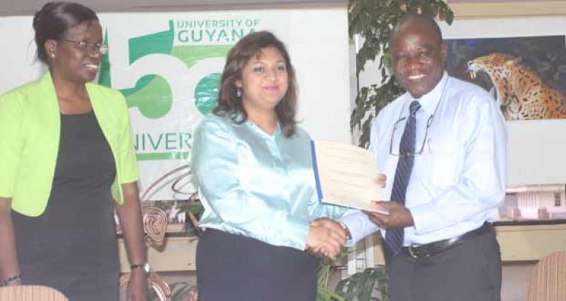 Education Minister, Ms Priya Manickchand hands over the relevant documentation to UG Vice-Chancellor, Professor Jacob Opadeyi