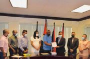Home Affairs Minister, Robeson Benn, submitting the signed contract to the contractor, Nazar Mohammed in the company of others