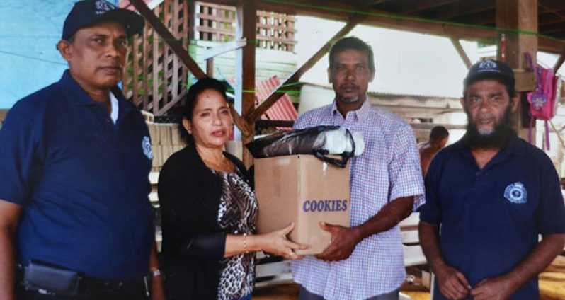 Liaison Officer of the Number 75 Village CPG, Radica Ramanandan presents several items to the relative of Dochan Sukra, one of the missing fishermen suspected to have been killed by pirates in the Corentyne River late last month