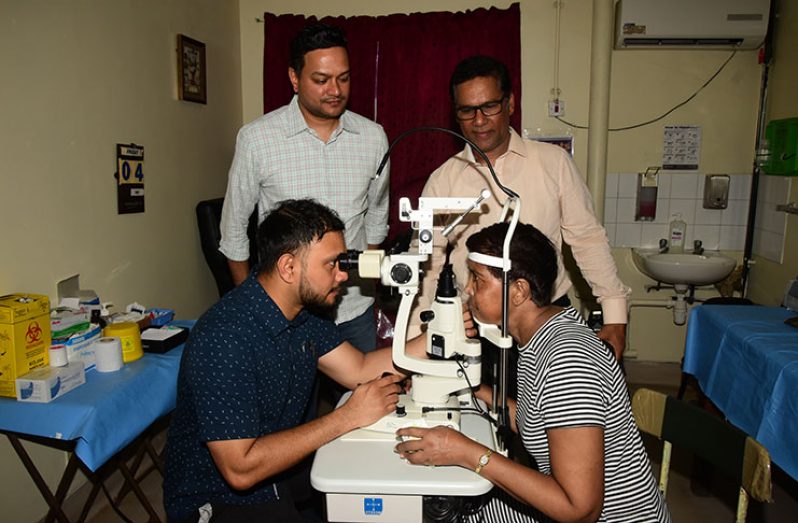Dr. Sugrim conducts an eye test while members of the foundation, Tony Subraj and Richard Mahase look on (Adrian Narine photo)