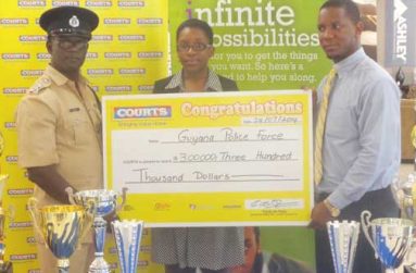 Marketing Manager Purnell Cummings (right) and Public Relations Officer Roberta Ferguson hand over the $300 000 cheque to Colin Boyce of the Guyana Police Force, yesterday.