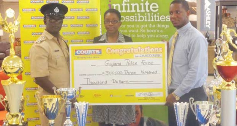 Marketing Manager Purnell Cummings (right) and Public Relations Officer Roberta Ferguson hand over the $300 000 cheque to Colin Boyce of the Guyana Police Force, yesterday.