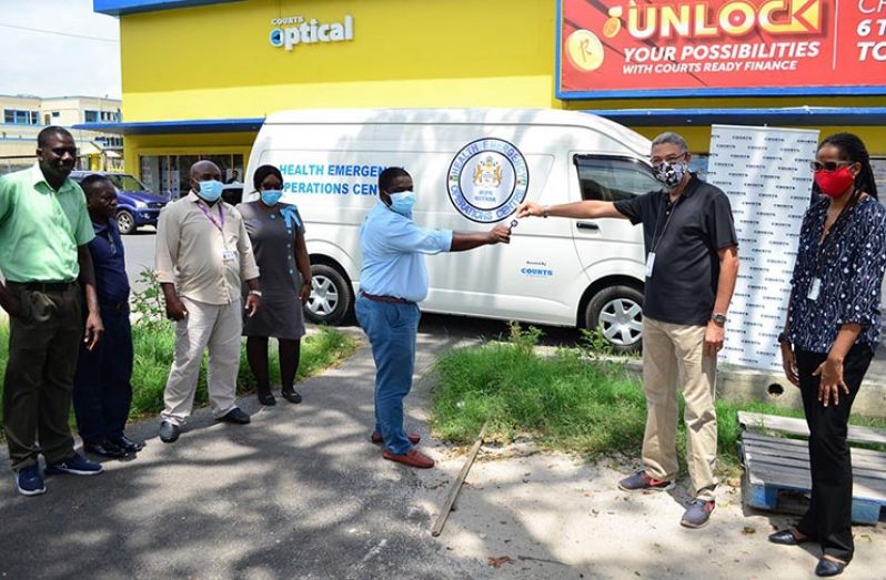Managing Director of Unicommer Guyana, Clyde De Hass (right) hands over the key to the emergency response bus to Dr. Leston Payne, Head of the Heath Emergency Response Committee, Ministry of Public Health, as other officials look on
