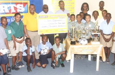 Co-Director of Petra Organisation Troy Mendonca (5th from left), Deputy CEO of the Education Ministry Marcel Hudson and COURTS Marketing Manager Pernell Cummings are surrounded by some students from the participating schools at yesterday’s COURTS Pee Wee Football launch. (Sonell Nelson photo)