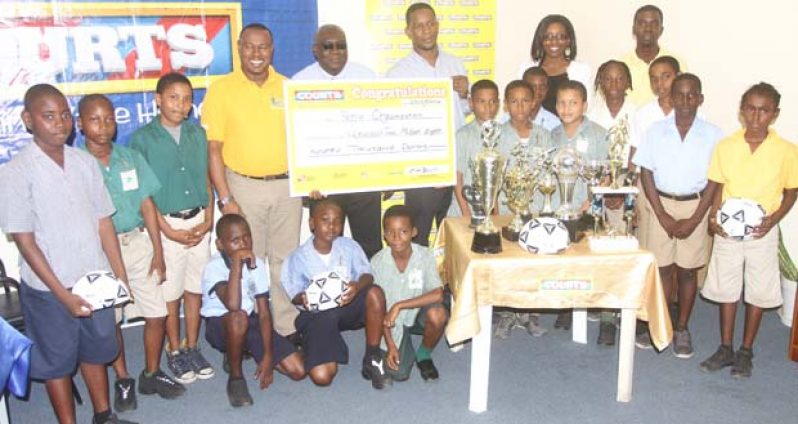 Co-Director of Petra Organisation Troy Mendonca (5th from left), Deputy CEO of the Education Ministry Marcel Hudson and COURTS Marketing Manager Pernell Cummings are surrounded by some students from the participating schools at yesterday’s COURTS Pee Wee Football launch. (Sonell Nelson photo)