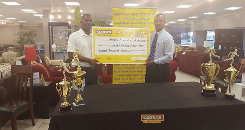 COURTS Marketing Manager Pernell Cummings (left) hands over the cheque to AAG president Aubrey Hutson.