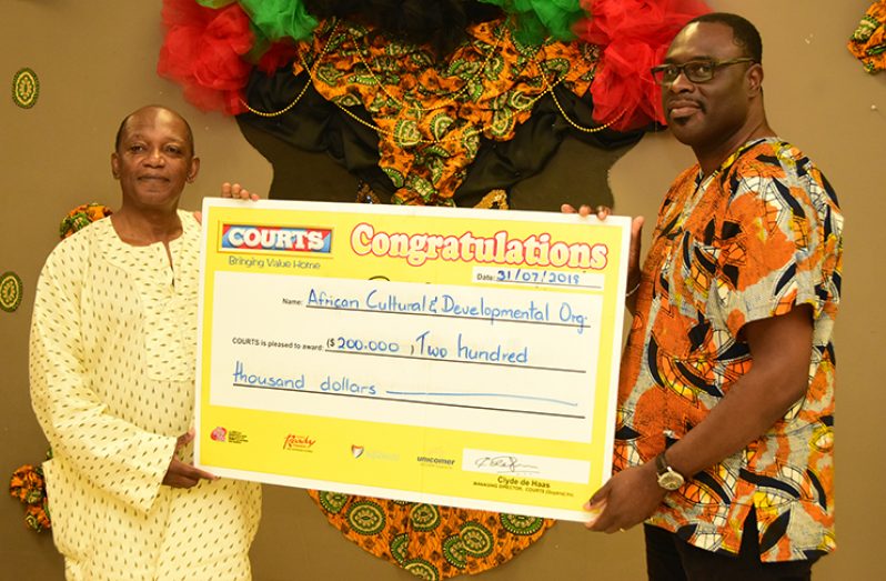 Eric Phillips, an executive of ACDA (left) receiving Courts’ donation to Emancipation celebrations. (Adrian Narine photo)