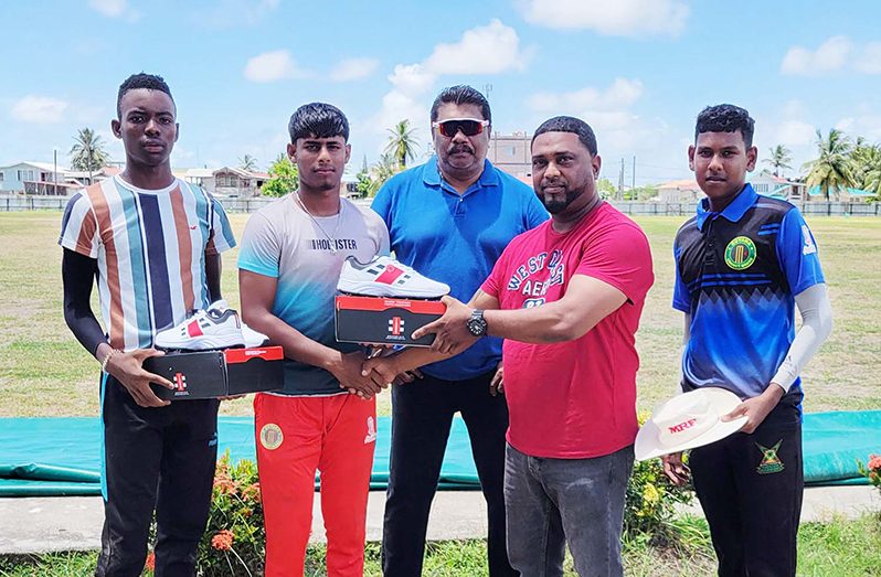 Marvin Abbensett, right, hands over one pair of cricket shoes to Afraz Budhoo in the presence of his team-mates and Anil Beharry.