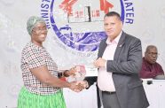 Minister of Housing and Water Collin Croal and one of the recipients of the building materials vouchers valued at $250,000  