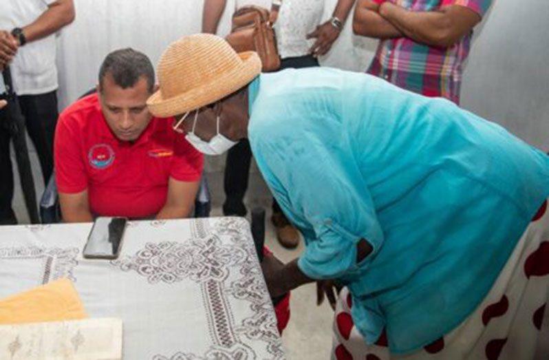 Housing and Water Minister Collin Croal assisting a resident of Walton Hall with a land issue (DPI photo)