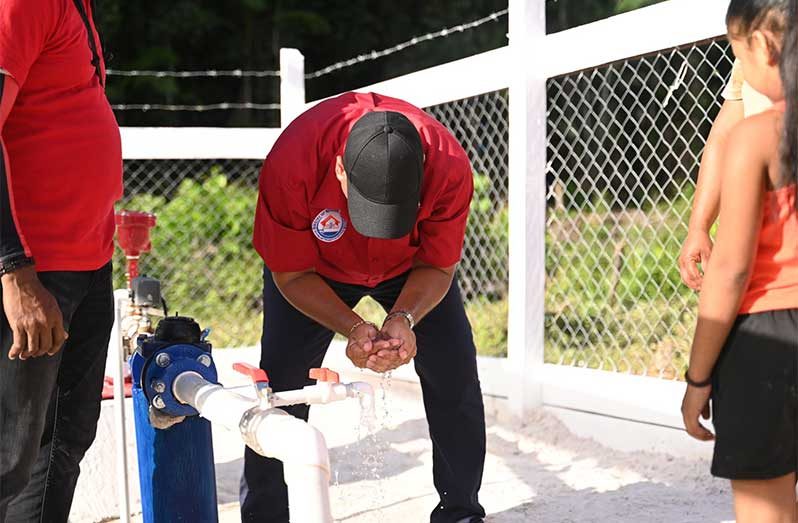 Minister of Housing and Water, Collin Croal, drinks water from the distribution network following the commissioning of a new water supply system on Monday