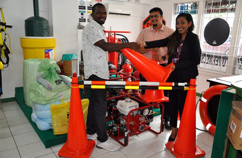 Crystal Kallu, Administrative Assistant of Industrial Safety Supplies Inc, hands over one of the cones to GCF’s Horace Burrowes in the presence of Stanton Seepersaud, Assistant Manager.