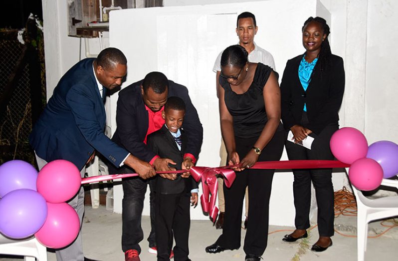 Petra Director Troy Mendonca assists a youngster in the cutting of the ribbon on Monday evening to unveil the lights at the Ministry of Education ground, Carifesta Avenue. Also in the photo are Minister of Education Nicolette Henry (third from left), GFF president Wayne Forde (extreme left) and Ansa McAl representative Shawn Abel. (Adrian Narine photo)