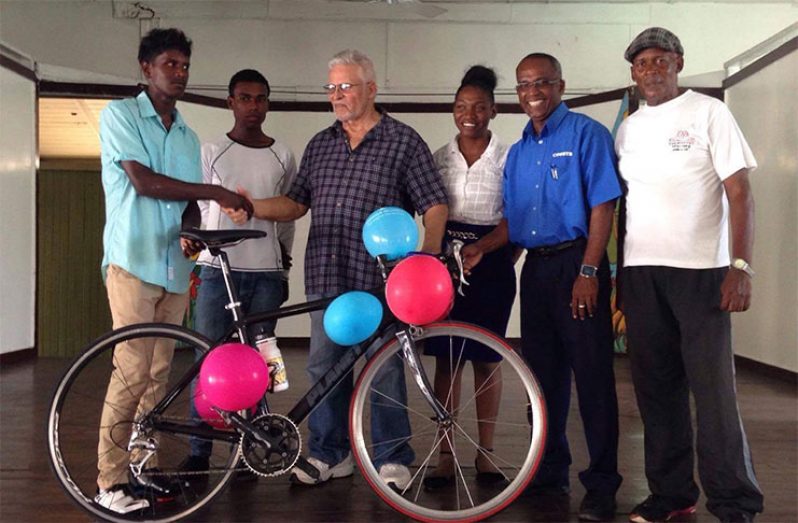 Young cyclist Ralph Seenarine (blue shirt) receives the donation of a racing bike, compliments of Franco Crawford.