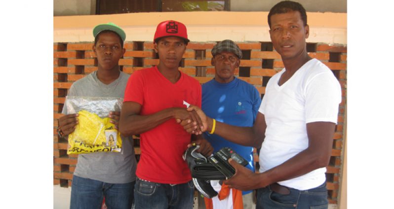 Franko Crawford (right) does the honours, as Coach Randolph Roberts looks on appreciatively